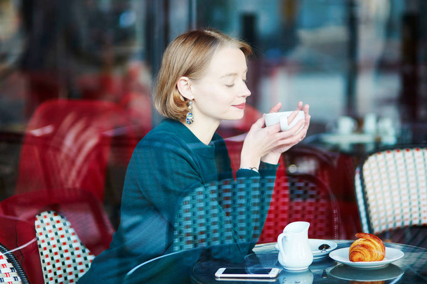 Young elegant woman drinking coffee in traditional cafe in Paris, France - Φωτογραφία, εικόνα