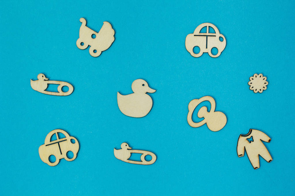 A set of wooden figures on a theme of a newborn on a blue backgr - Фото, изображение