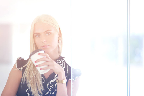 Businesswoman holding a cup of coffee standing in office . - Foto, immagini