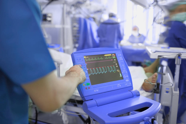 Médico que ajusta o monitor de ECG do paciente comatoso no
  - Foto, Imagem