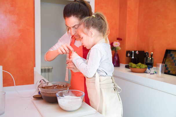 filha e mãe cozinhar um bolo juntos na cozinha
 - Foto, Imagem