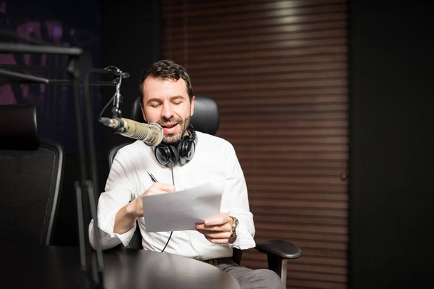 Retrato del joven presentador de radio masculino en la estación de radio con auriculares y micrófono
 - Foto, Imagen