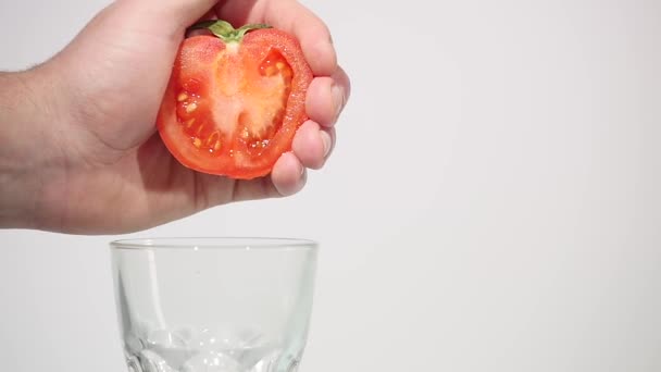 Hand squeezes juice from a tomato - Felvétel, videó