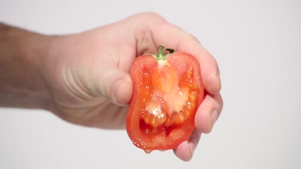 Hand squeezes juice from a tomato - Кадри, відео