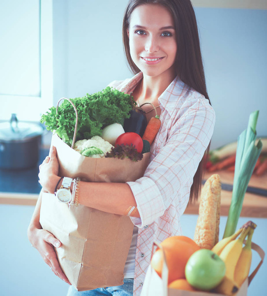 Young woman holding grocery shopping bag with vegetables  - 写真・画像