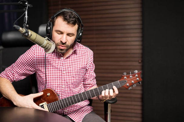 gitar çalmak ve radyo istasyonu mikrofon şarkı genç erkek şarkıcı - Fotoğraf, Görsel