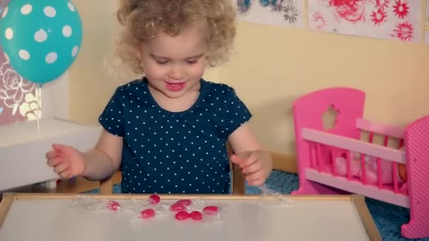 emotionele meisje speelt met zoete suikergoed op haar tafeltje - Video