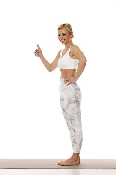 Yoga, Sport, Training und Lifestyle-Konzept. Porträt einer jungen schönen Frau in weißer Sportbekleidung auf weißem Hintergrund. - Foto, Bild