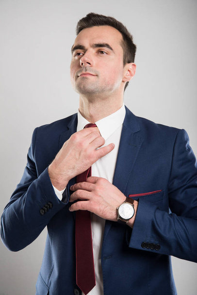 Portrait of young attractive business man arranging his tie - Foto, Bild
