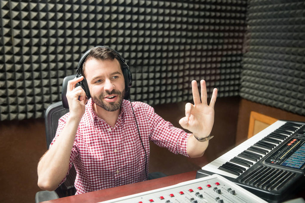 Male technician gesturing ok at sound mixing console in recording studio   - Photo, Image