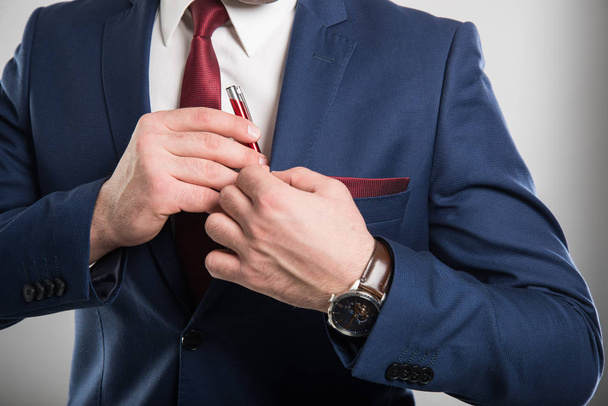 Close-up of business man wearing suit putting pen in pocket - Foto, imagen