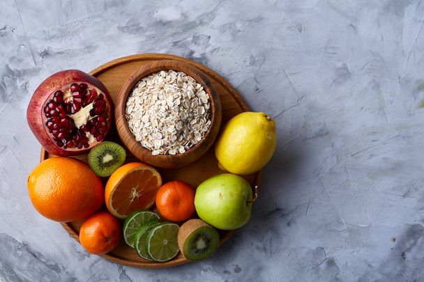 Bowl with oatmeal flakes served with fruits on wooden tray white background, flat lay, selective focus - Valokuva, kuva