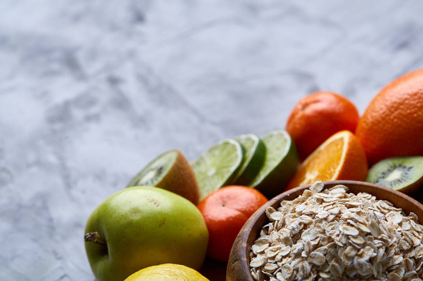 Bowl with oatmeal flakes served with fruits on wooden tray white background, flat lay, selective focus - 写真・画像