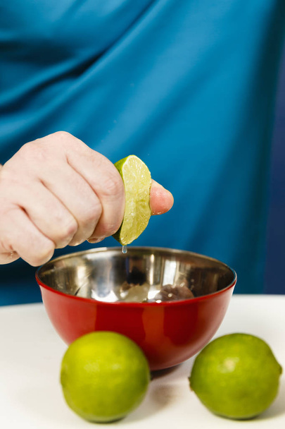 Man squeezing half a lime into a bowl, selective focus - Photo, Image