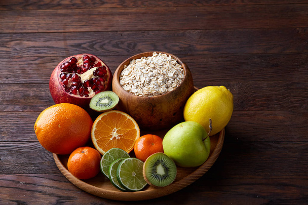 Bowl with oatmeal flakes served with fruits on wooden tray wooden background, flat lay, selective focus - Φωτογραφία, εικόνα