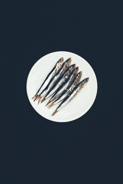 Vista superior de la pila salada de pescado en placa aislada en negro
 - Foto, Imagen