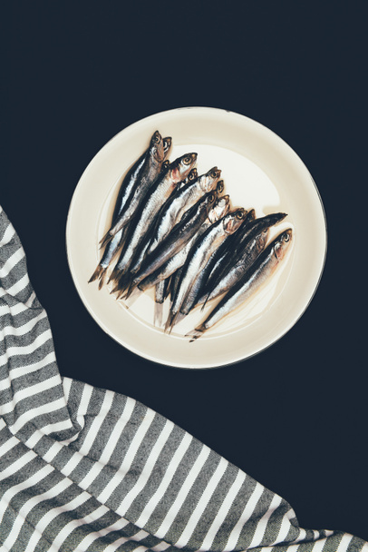Top view of pile of fish in plate and towel isolated on black - Photo, Image