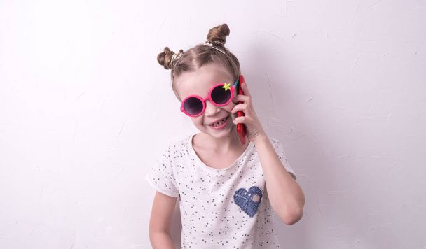 Communication technologies: A girl in pink glasses emotionally talks on the red phone. - Фото, зображення