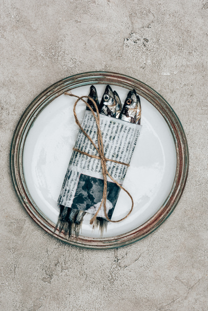 Pile of fish in newspaper wrapped by string on plate - Foto, immagini