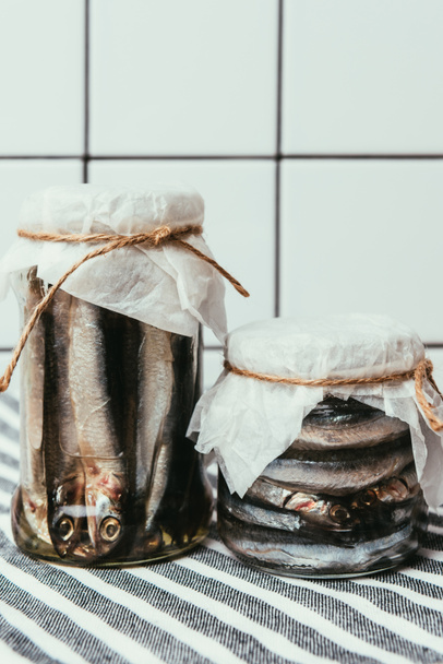 Kupie solone ryby w słoikach, zapakowane przez ciągi na ręcznik - Zdjęcie, obraz