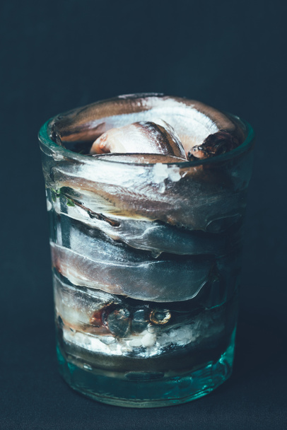 Pile of salted fish in glass isolated on black - Φωτογραφία, εικόνα