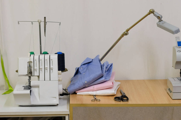 Sewing machine and shirts in a sewing studio - Fotó, kép