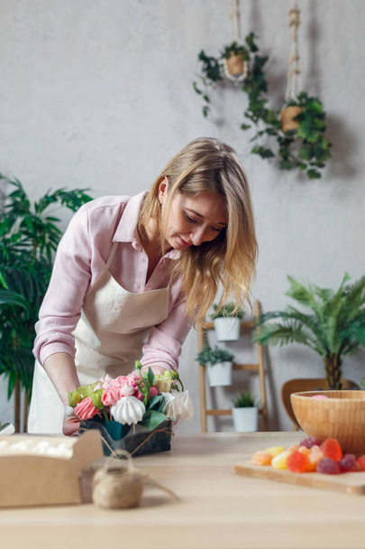 Image of florist composing bouquet at table on background of flowers - Zdjęcie, obraz