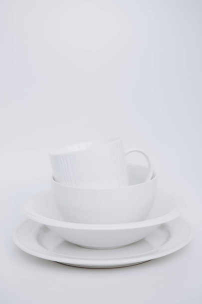 white utensils three plates cup white background vertical frame - Fotoğraf, Görsel