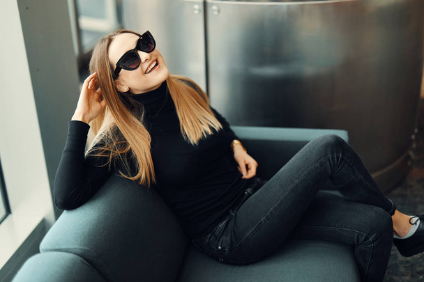 Young pretty girl sit on the sofa wear glasses and smile to came - Фото, изображение