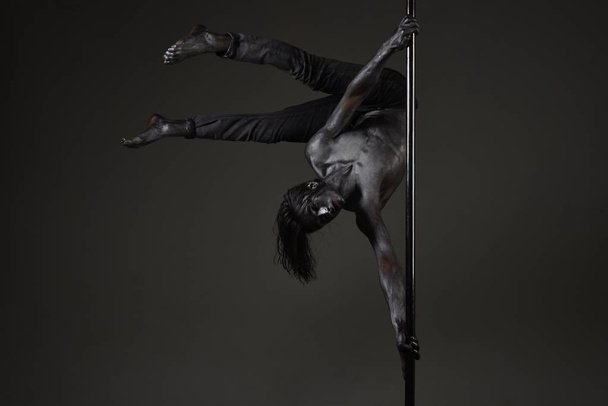 Athlete, sportsman performing pole dancing moves, work out, show trick. - Фото, изображение