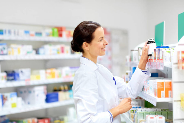 happy female apothecary with drug at pharmacy - Foto, imagen