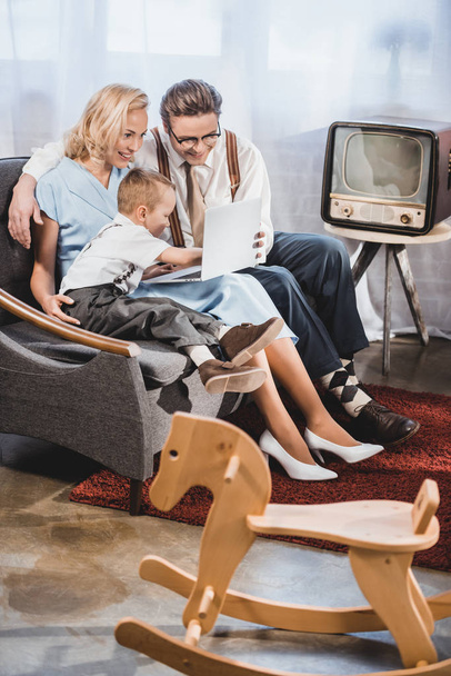 cheerful 1950s style family using laptop together at home  - Fotó, kép
