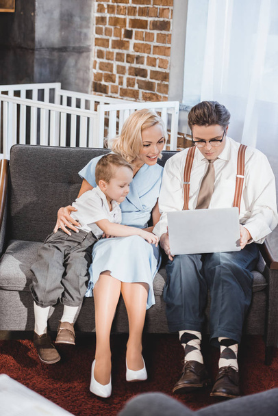 smiling 50s style family using laptop together at home  - Foto, Bild