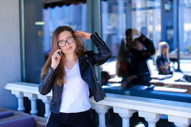 Heureuse personne féminine dans des lunettes parlant par smartphone au café
. - Photo, image