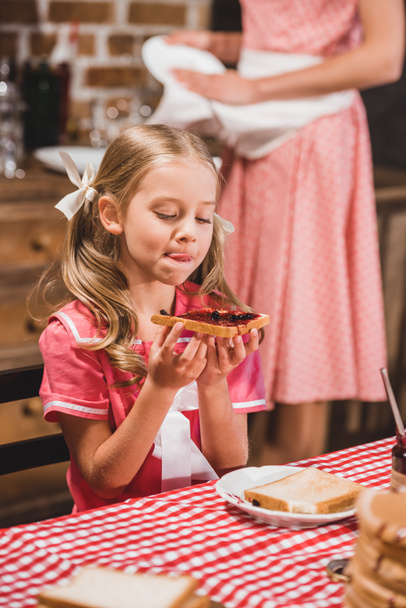 entzückendes kleines Mädchen hält köstlichen Toast mit Marmelade zum Frühstück - Foto, Bild