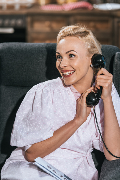 счастливая блондинка в халате разговаривает по старинному телефону и смотрит в сторону
 - Фото, изображение