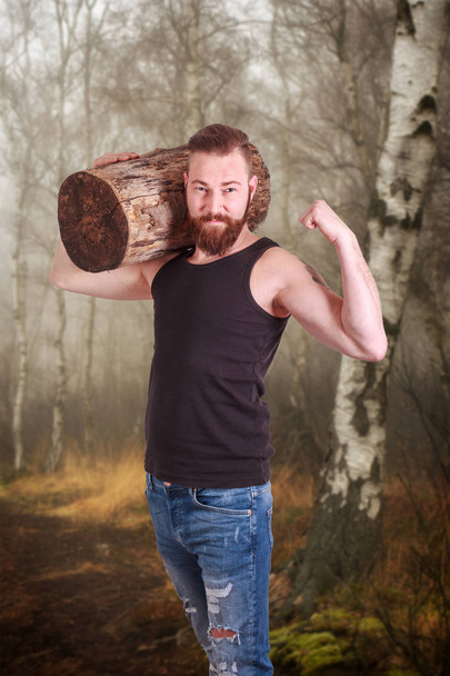 Bearded man wearing log on his shoulder - Photo, Image
