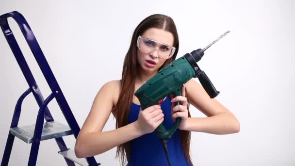 sexy girl posing with a drill on a white studio with a stepladder. concept - beauty and strength, feminism - Footage, Video