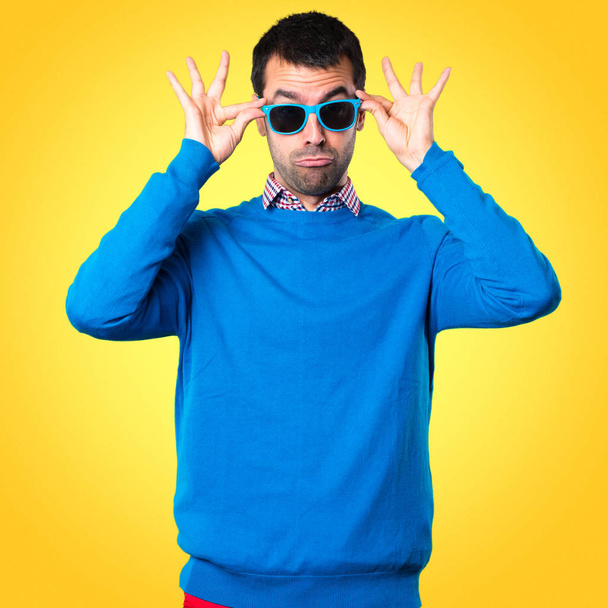 Knappe jonge man met zonnebril op kleurrijke achtergrond - Foto, afbeelding