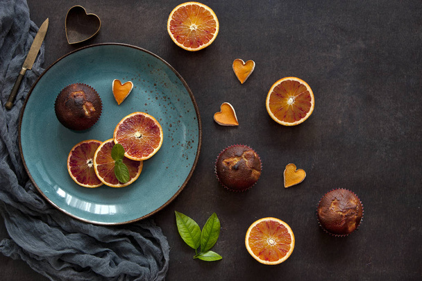 close-up of chocolate cupcakes with oranges on plate with scarf on dark table - Foto, Imagen