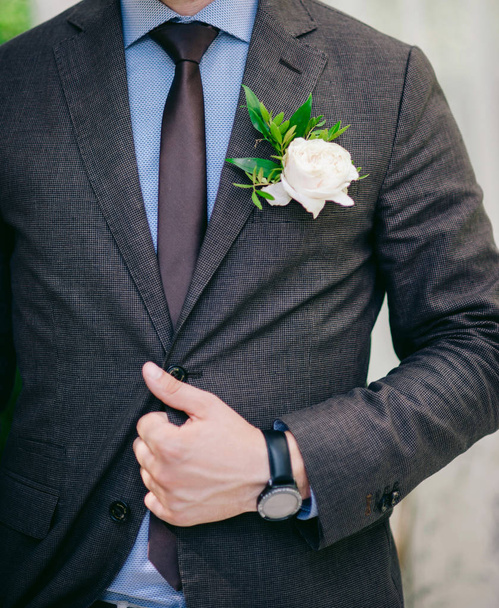 Groom adjusts jacket with boutonniere - Photo, Image