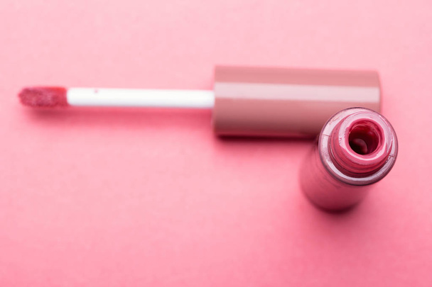 Cepillo para labios de maquillaje y la botella de lápiz labial líquido de cerca sobre un fondo rosa con espacio para copiar - Foto, Imagen