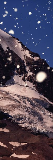 Snow falling against snow capped mountain on a sunny day - Valokuva, kuva
