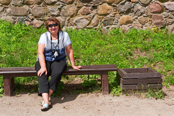 Middle-aged woman relaxing on a bench - Photo, Image