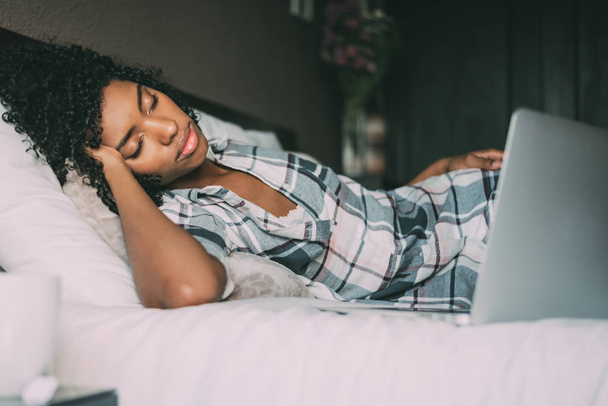 mooie zwarte vrouw op bed met laptop slapen - Foto, afbeelding