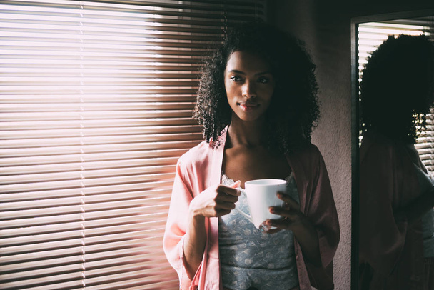 красива чорна жінка стоїть біля вікна з чашкою кави
 - Фото, зображення