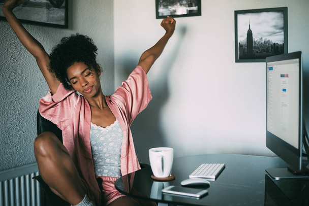 mujer negra en casa estiramiento con computadora y café por la mañana
 - Foto, imagen