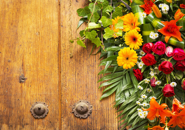 Bloemen krans op verweerde houten deur met kopie ruimte - Foto, afbeelding