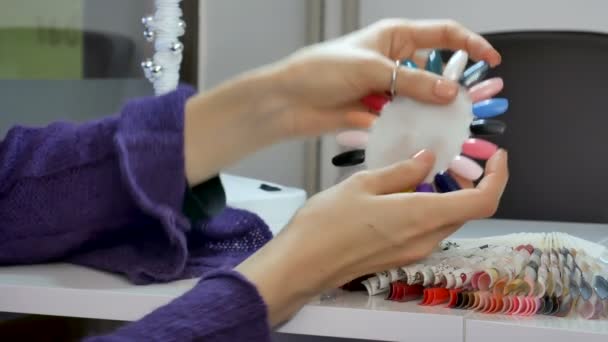 ゲルのクローズ アップのビデオは、美容院でのカラー配列パレットを爪します。紫外線を選択する女性の手の爪の色. - 映像、動画