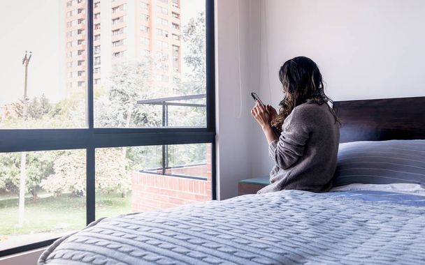 Donna latina che guarda il cellulare nella sua camera da letto, decima foto
 - Foto, immagini